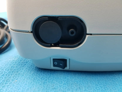 Light blue plastic salter labs aire elite compressor nebulizer with black circular port and power switch on the back side