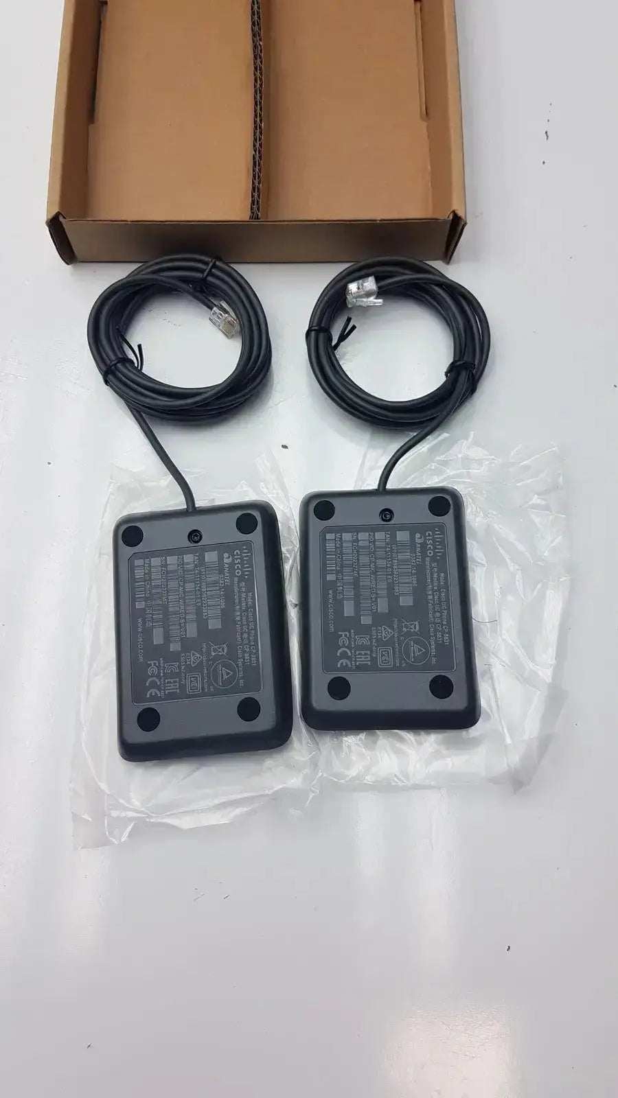 Image of the back side of two black cisco uc phone network switches with coiled ethernet cables for conference phone microphone use