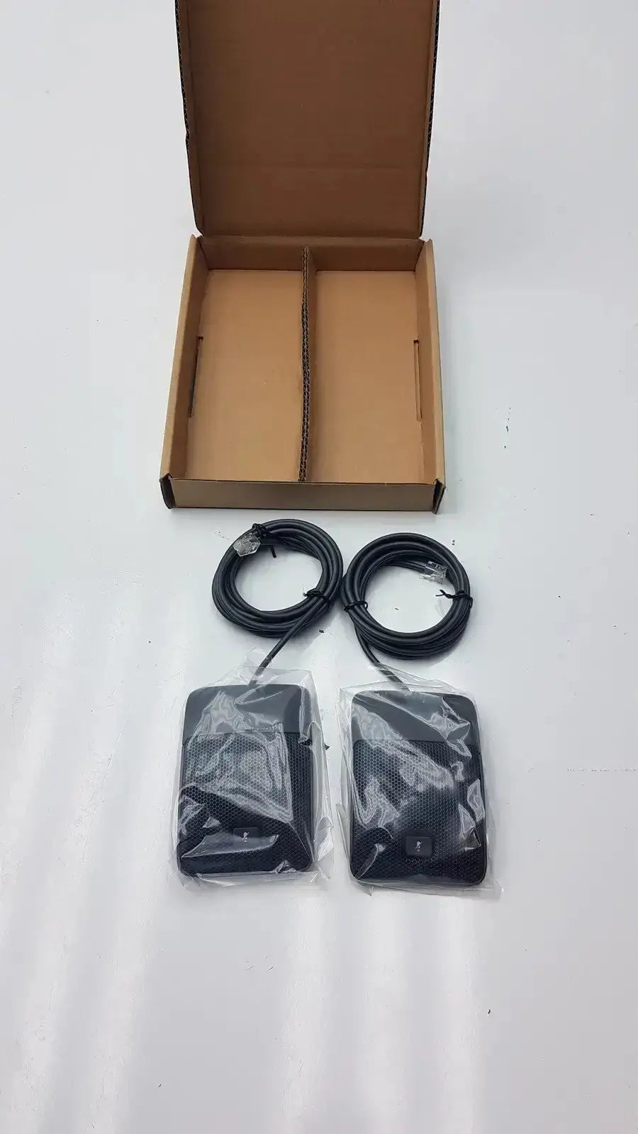 Two black rectangular cisco uc phone wireless access points wrapped in clear plastic for conference phone microphone use