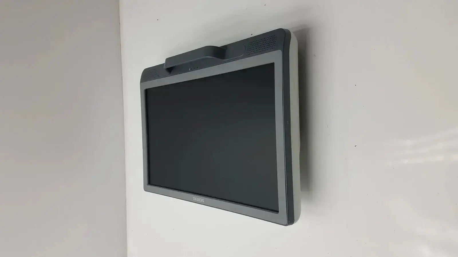 Gray plastic Siemens kt-lm215fds fhd flat panel display monitor with black screen and small handle mounted on wall
