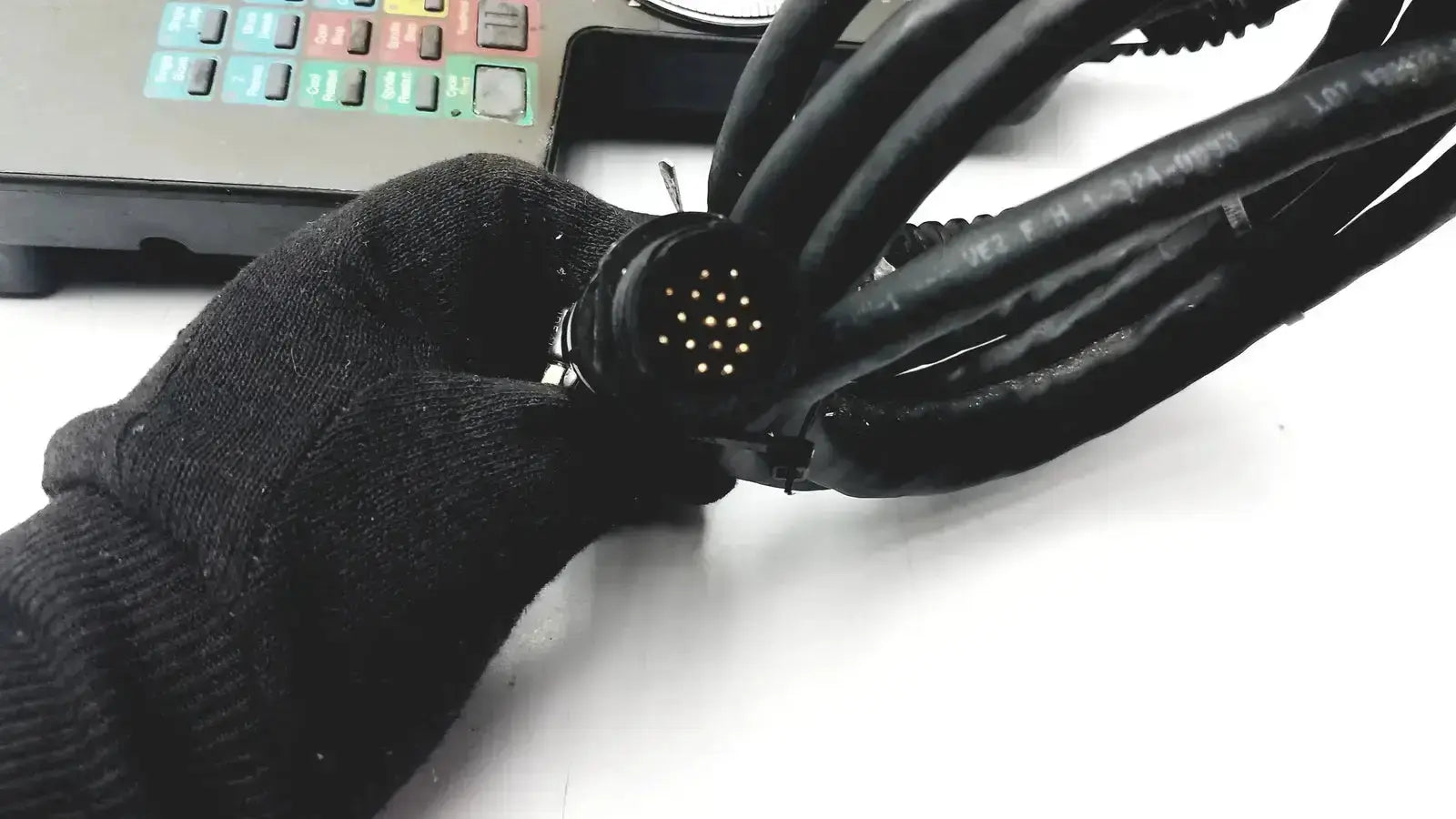 Black multi-cable connector with circular 24-pin interface held by gloved hand for siemens cincinnati milacron cnc lathe teach pendant controller
