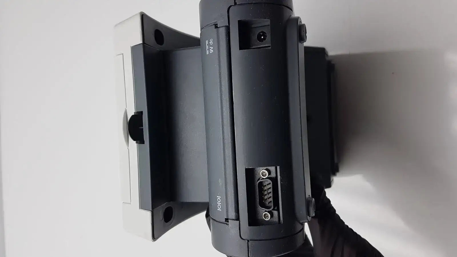 Black plastic siemens clinitek status analyzer with white mounting bracket and visible serial connector ports back view