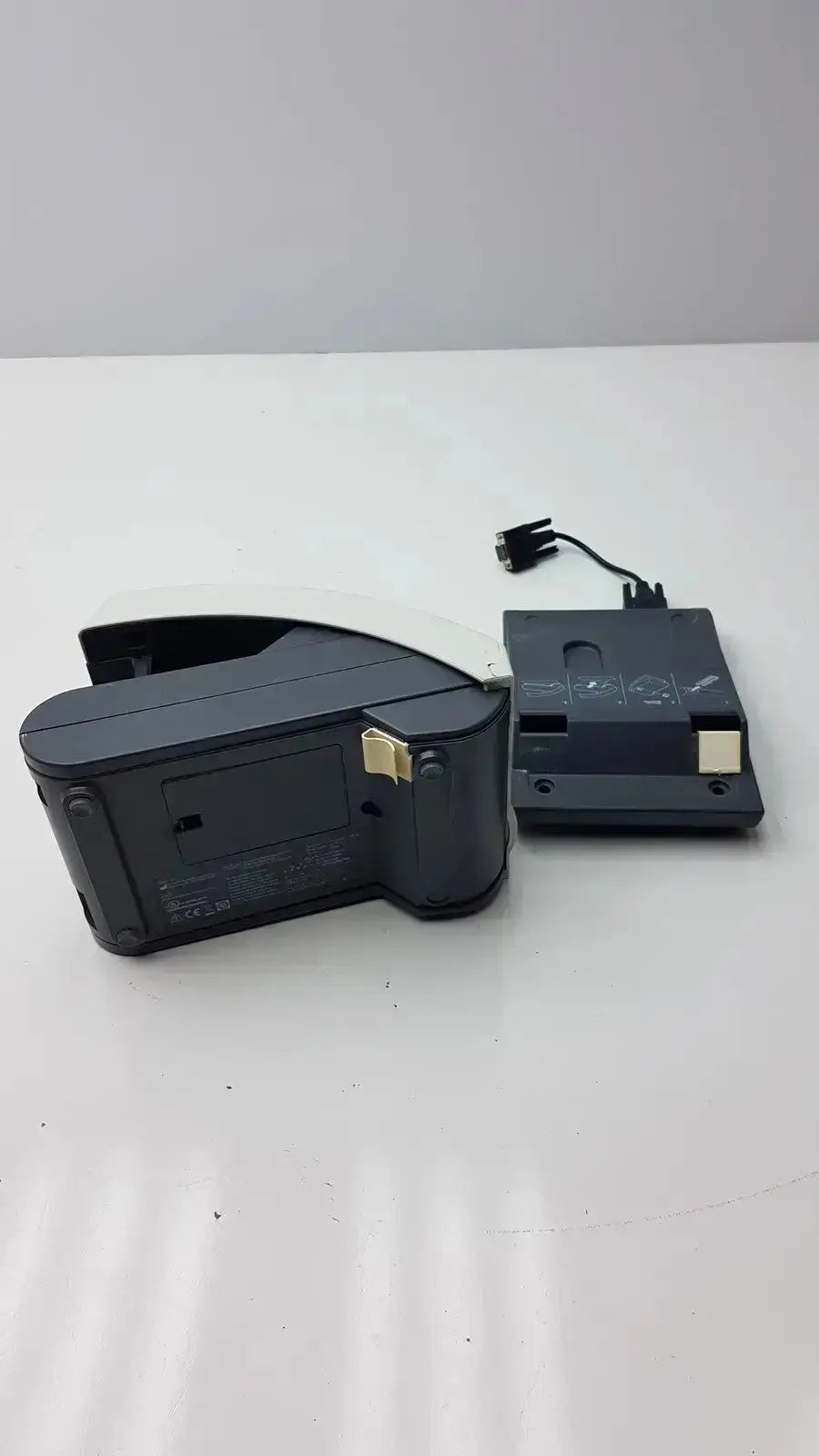 Black plastic nintendo switch dock with gold connectors and power cable attached showing back side for siemens clinitek status analyzer model 004979