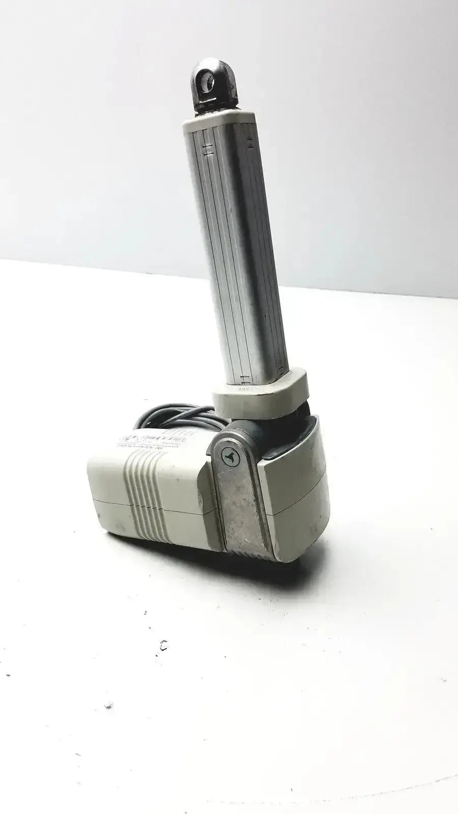Gray metallic skf actuation linear actuator with cylindrical arm and coiled black cable from hospital surplus