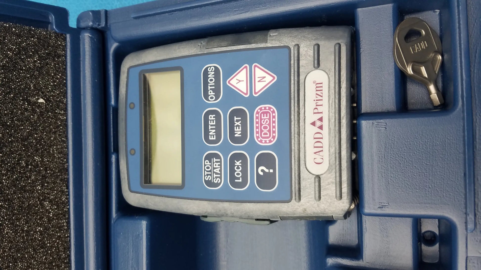 Gray and blue cadd prizm medical equipment with digital display and buttons attached to smiths medical 6100 pump case