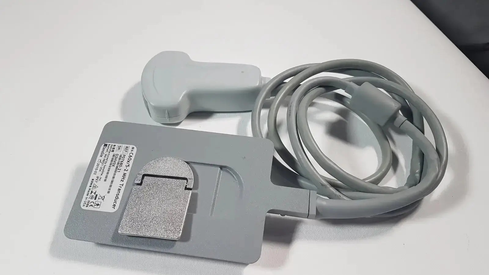 Gray sonosite c60x 5-2 mhz ultrasound transducer p07680-21 with coiled cable and silver metallic base plate shown from the back