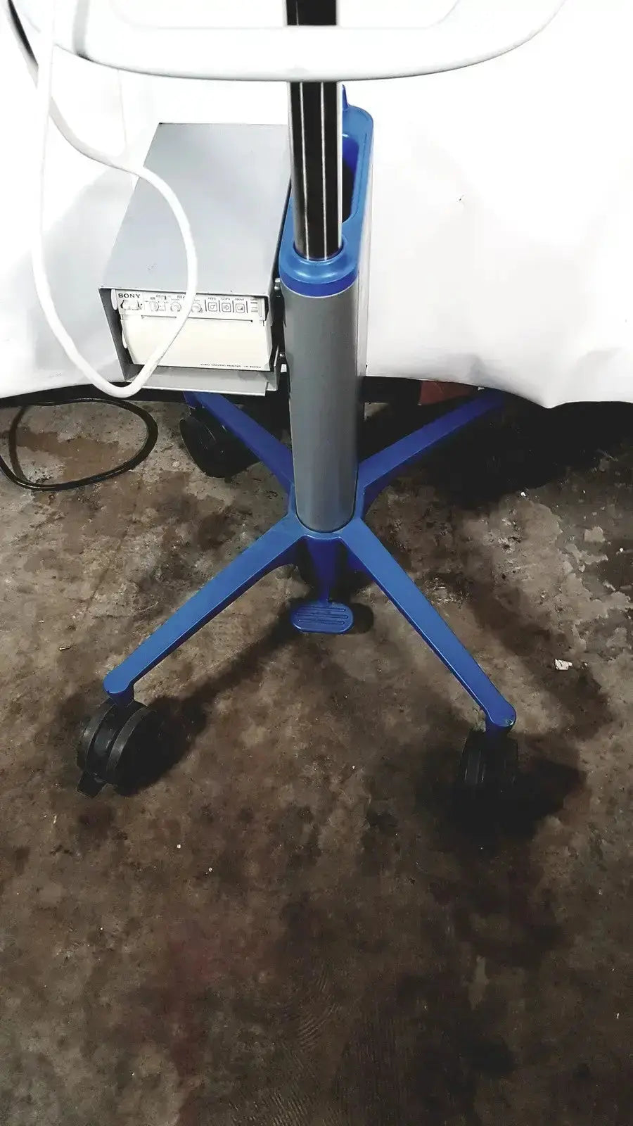 Blue plastic office chair with gray column and caster wheels beside sonosite l38 mhz linear transducer on rolling stand