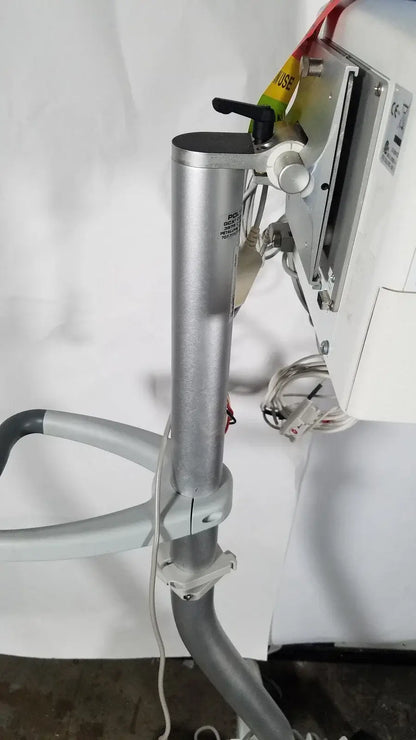 Silver cylindrical metal pole with black handle and white knob mounted on gray articulated arm of spacelabs patient monitor rolling stand medical equipment