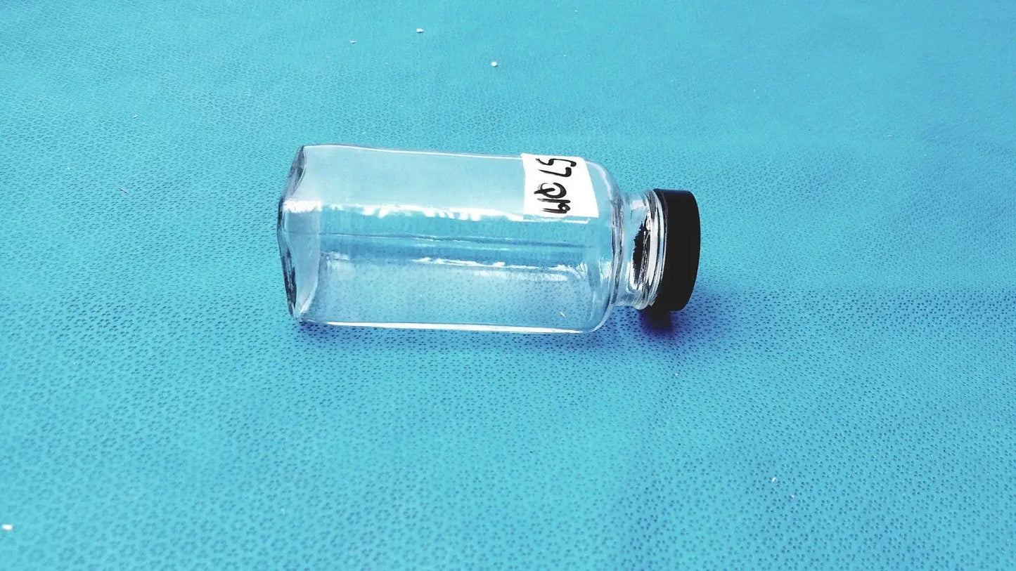 Clear square glass bottle with black cap and white label for laboratory reagent or reuse medical equipment storage