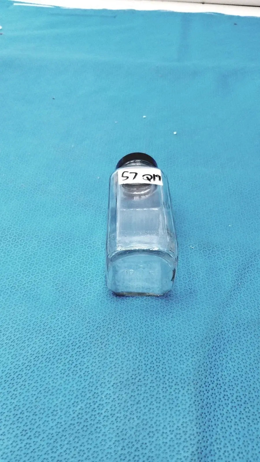Square clear glass bottle with black lid and white label for medical equipment reuse and laboratory reagent storage
