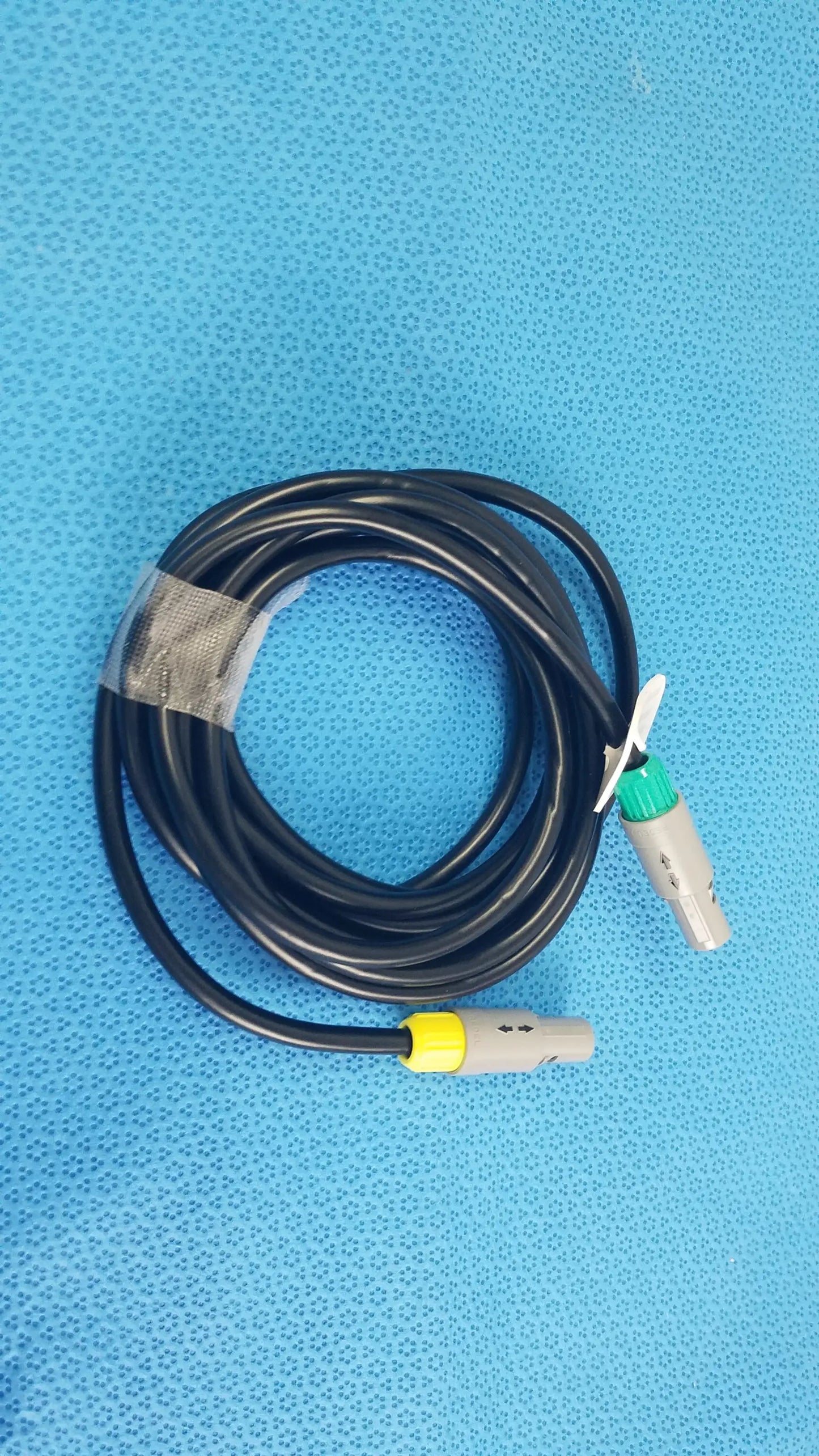 Black coiled catheter connection cable with gray connectors and green and yellow accents for reuse medical equipment