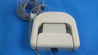 Off-white plastic stokert smartablate system foot pedal ref m490005 with coiled gray cable and sensor slot for medical equipment reuse