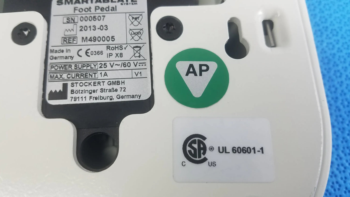 White plastic Stokert SmartAblate System foot pedal ref M490005 with black labeling and green ap certification sticker for medical equipment reuse