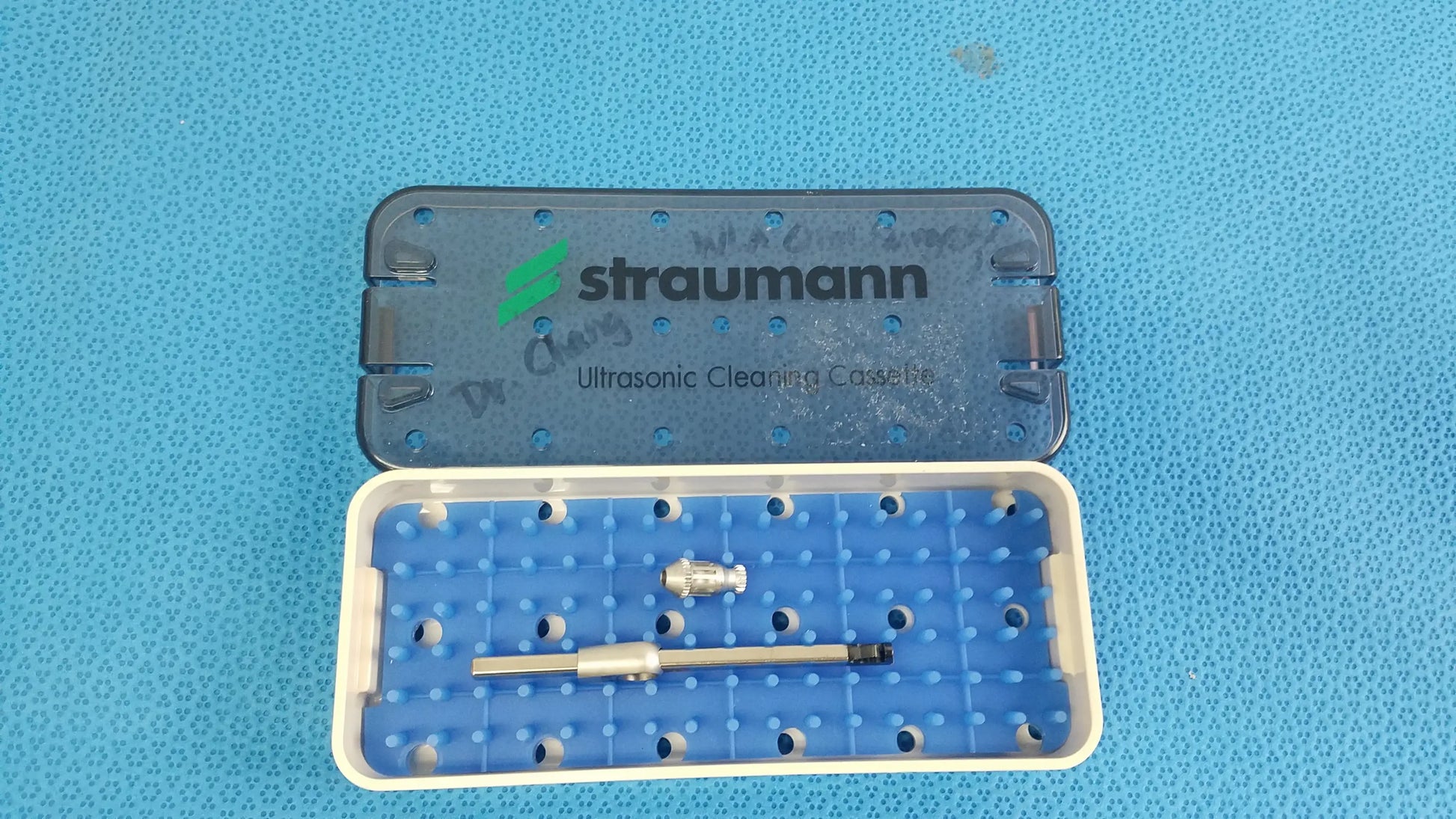Blue and white plastic Straumann ultrasonic cleaning cassette with silver surgical instruments for reuse medical equipment