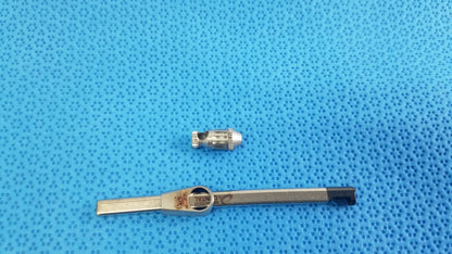 Silver metal valve stem cap with black handled tool included in straumann ultrasonic cleaning cassette for reuse medical equipment