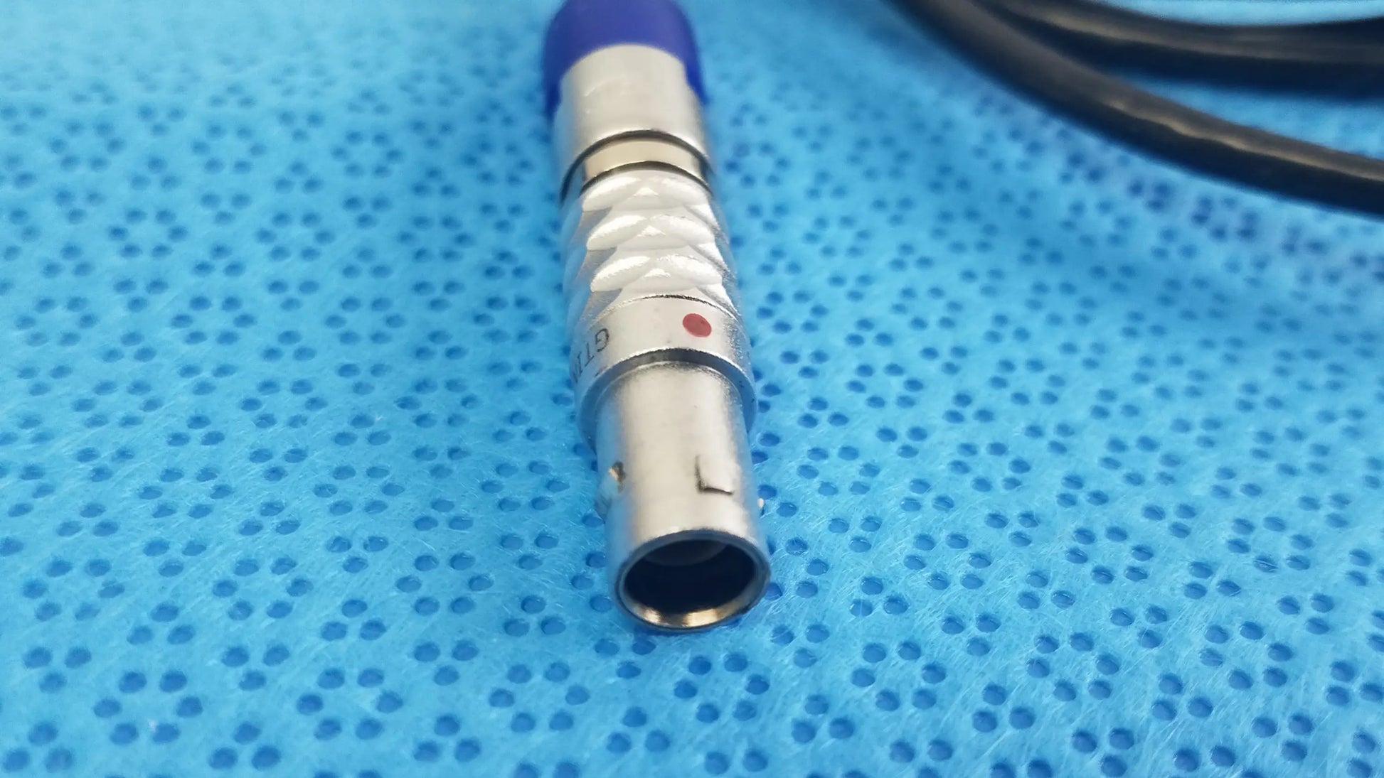 Silver medical-grade connector with blue cap and red dot on stryker multiGen 2 lightweight sterilization box for reuse medical equipment
