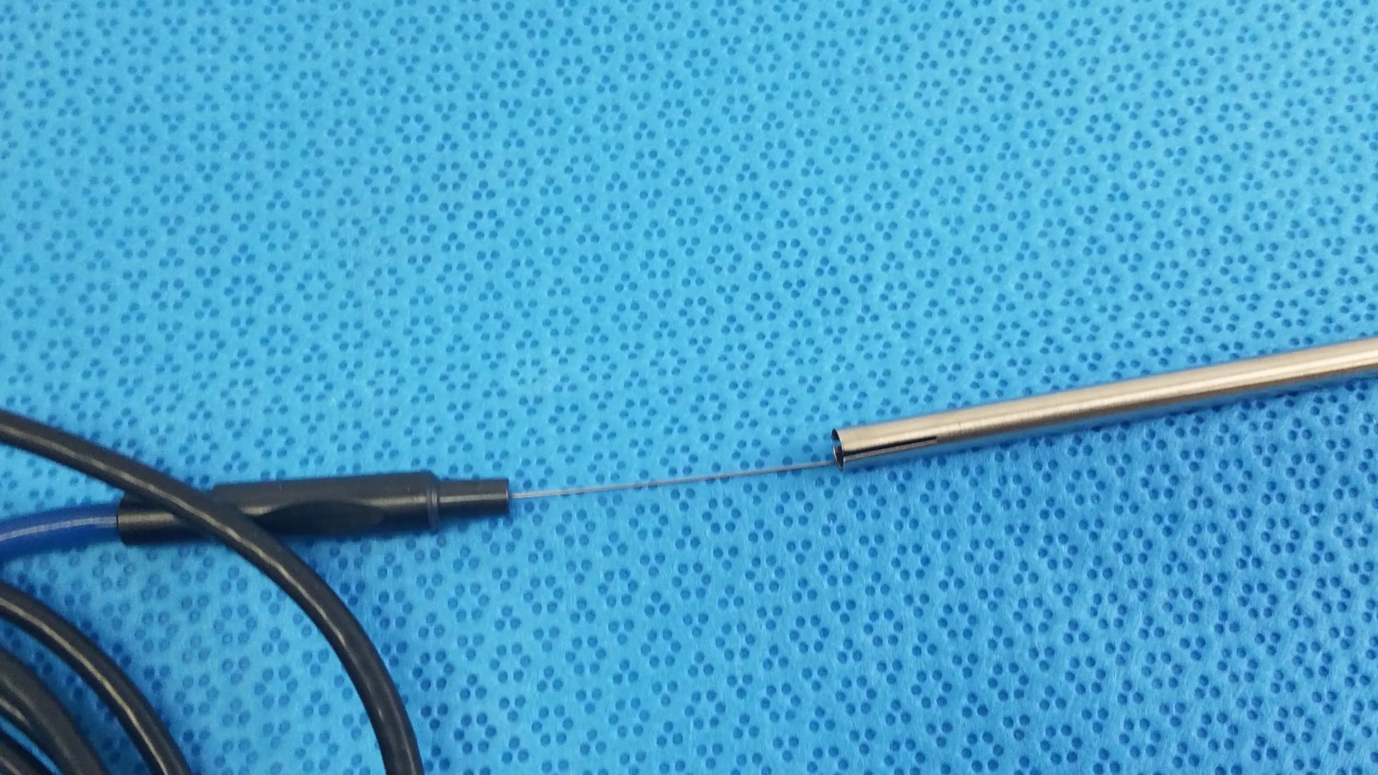 A sleek metallic electrode probe with black cable on blue surface for Stryker lightweight sterilization box medical equipment
