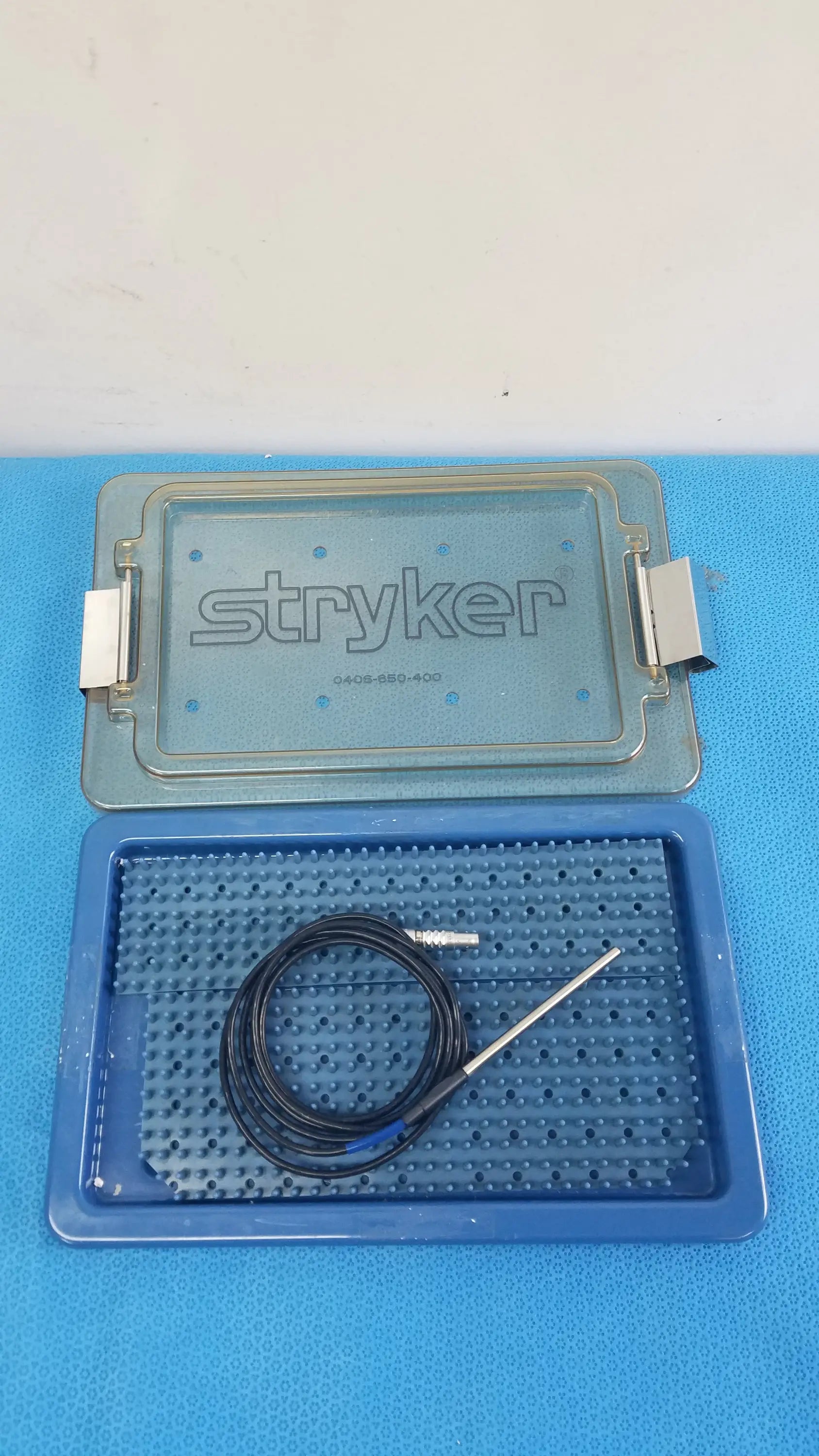 Blue stryker 0406-650-400 sterilization box with black coiled cable and metallic electrode probe for reuse medical equipment