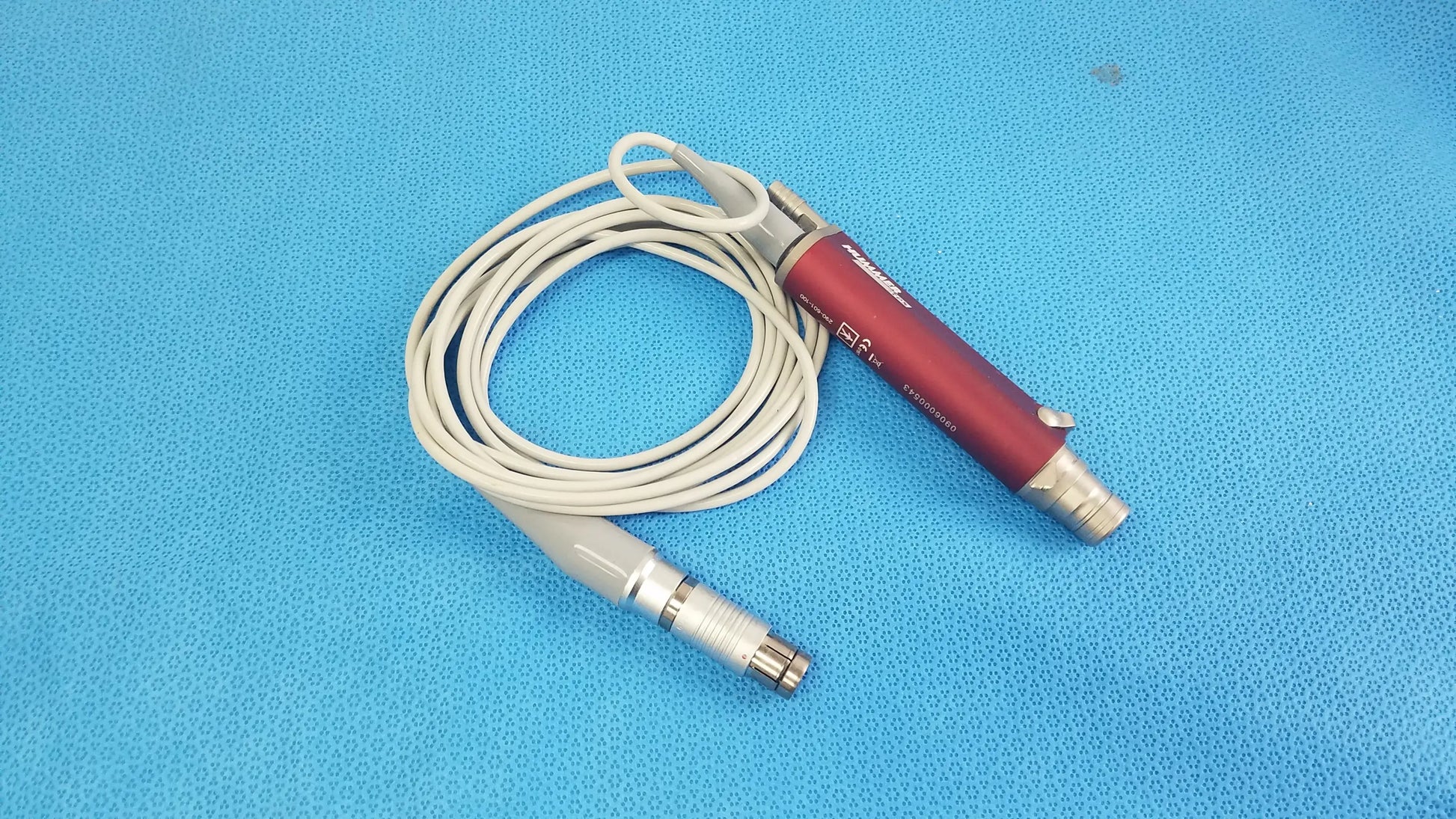 Red and silver tps leibinger hummer shaver handpiece with coiled white cable for precise surgical use