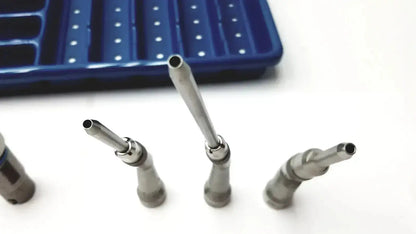 Set of four metallic dental drill attachments with varying tips arranged in front of blue Stryker core sterilization case