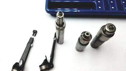 Silver metallic cylindrical tool bits with threaded ends and textured grips alongside precision instruments in a core sterilization case