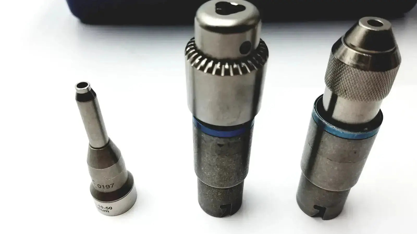Three metallic drill bits with blue accents in a stryker 5400-277 core sterilization case for surgical use