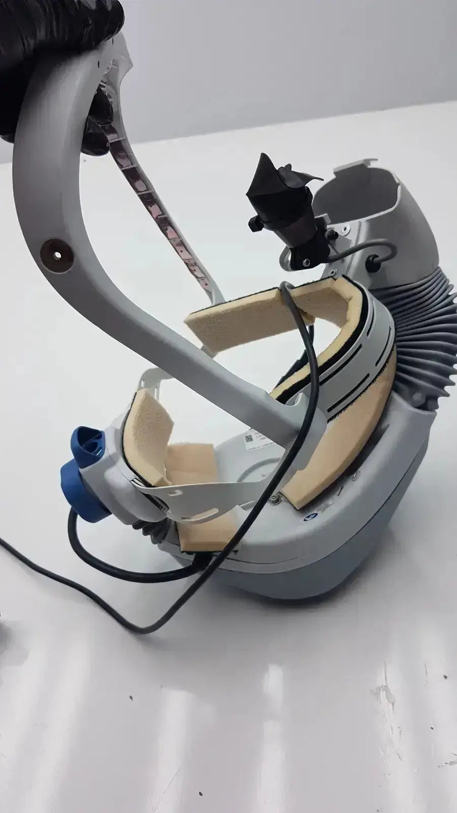 Gray and beige medical-grade stryker flyte helmet with adjustable straps black connectors and blue port for surgical use