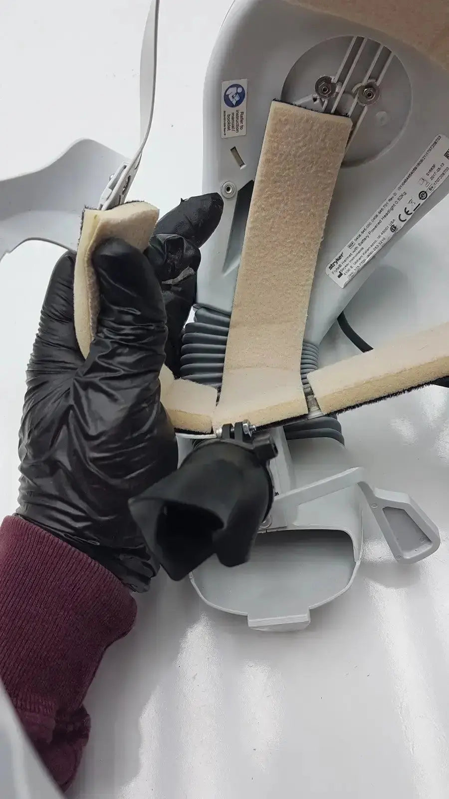 A beige textured foam strip held by a gloved hand for stryker flyte helmet ref 0408-645-000