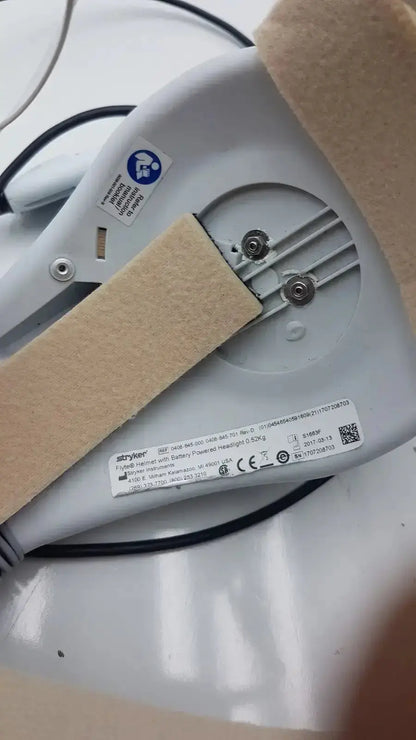 White plastic stryker flyte helmet with beige foam padding and metallic screws for hybrid vaginal delivery use