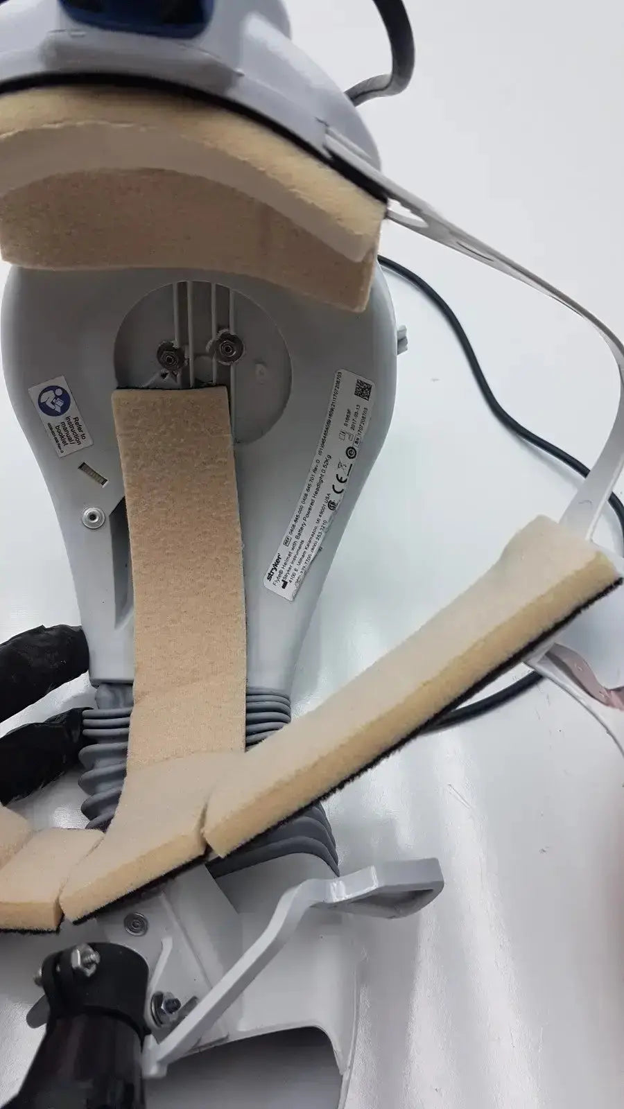 Gray bmw electric lawn mower with beige foam padding on handle and underside shown with stryker flyte helmet reference