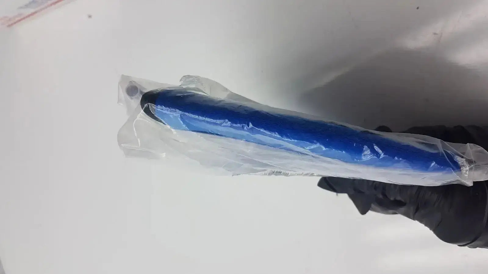 Blue suntech abpm cuff adult plus cylindrical cuff wrapped in clear plastic held by a gloved hand