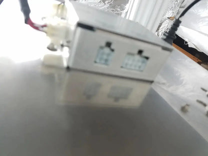 White plastic power supply unit with two input ports and black cable connected on the back side of sysmex ru-20 reagent delivery system
