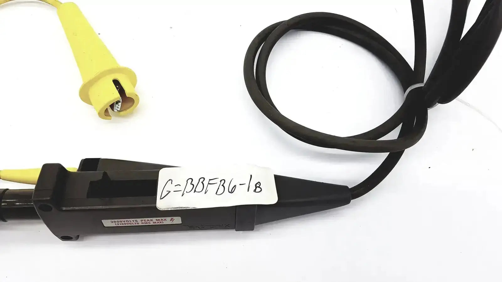 Black and yellow tektronix oscilloscope probe with coiled cable and insulated tip rated for 3000 volts peak max