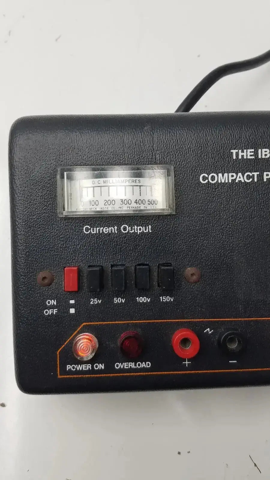 The IBI CPS 500 compact power supply is a black textured plastic unit with current output meter and red indicator lights