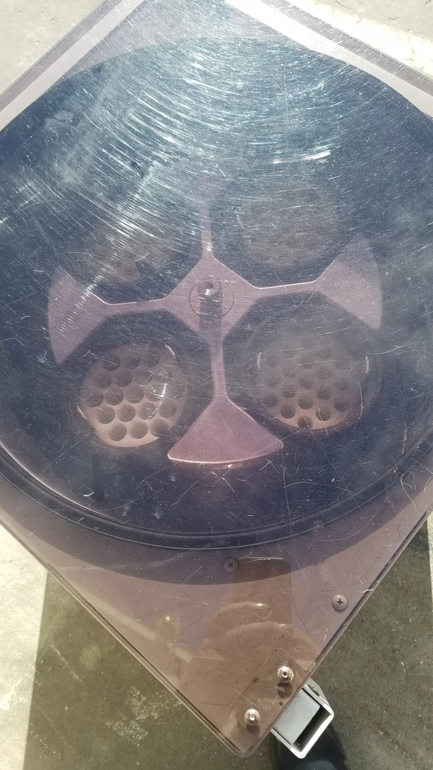 A dusty black plastic lid with a metallic cross and perforations for the silent solution silencer medical equipment system