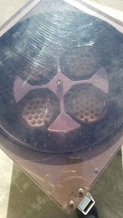 A dusty black plastic lid with a metallic cross and perforations for the silent solution silencer medical equipment system