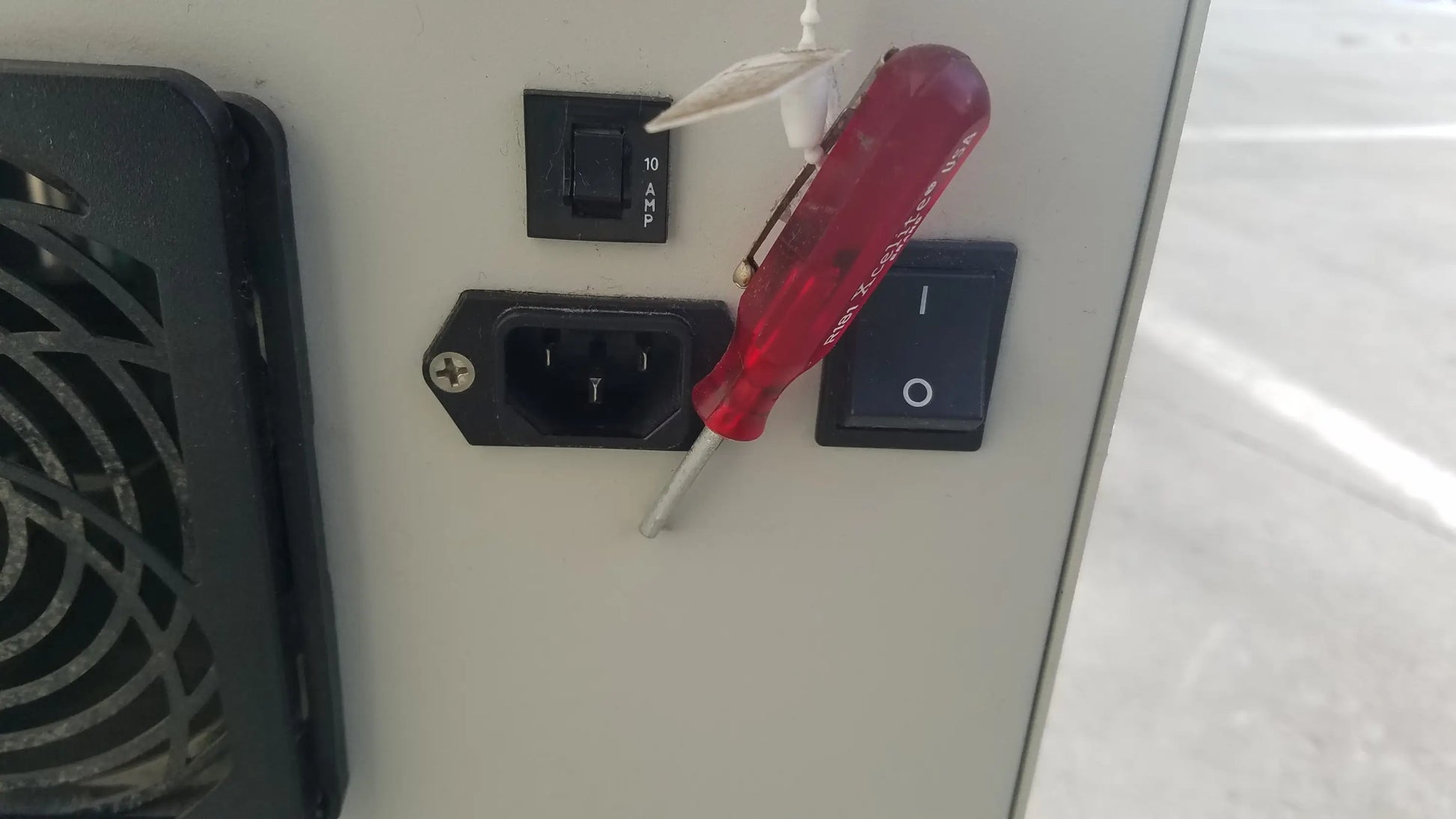 Red plastic screwdriver with metallic tip resting on electrical panel for silent solution silencer 2310 centrifuge system medical equipment