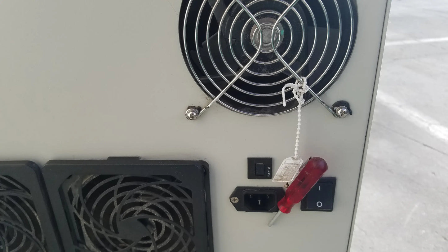 Red plastic screwdriver resting on a black power outlet at the back of the silent solution silencer 2310 centrifuge system medical equipment