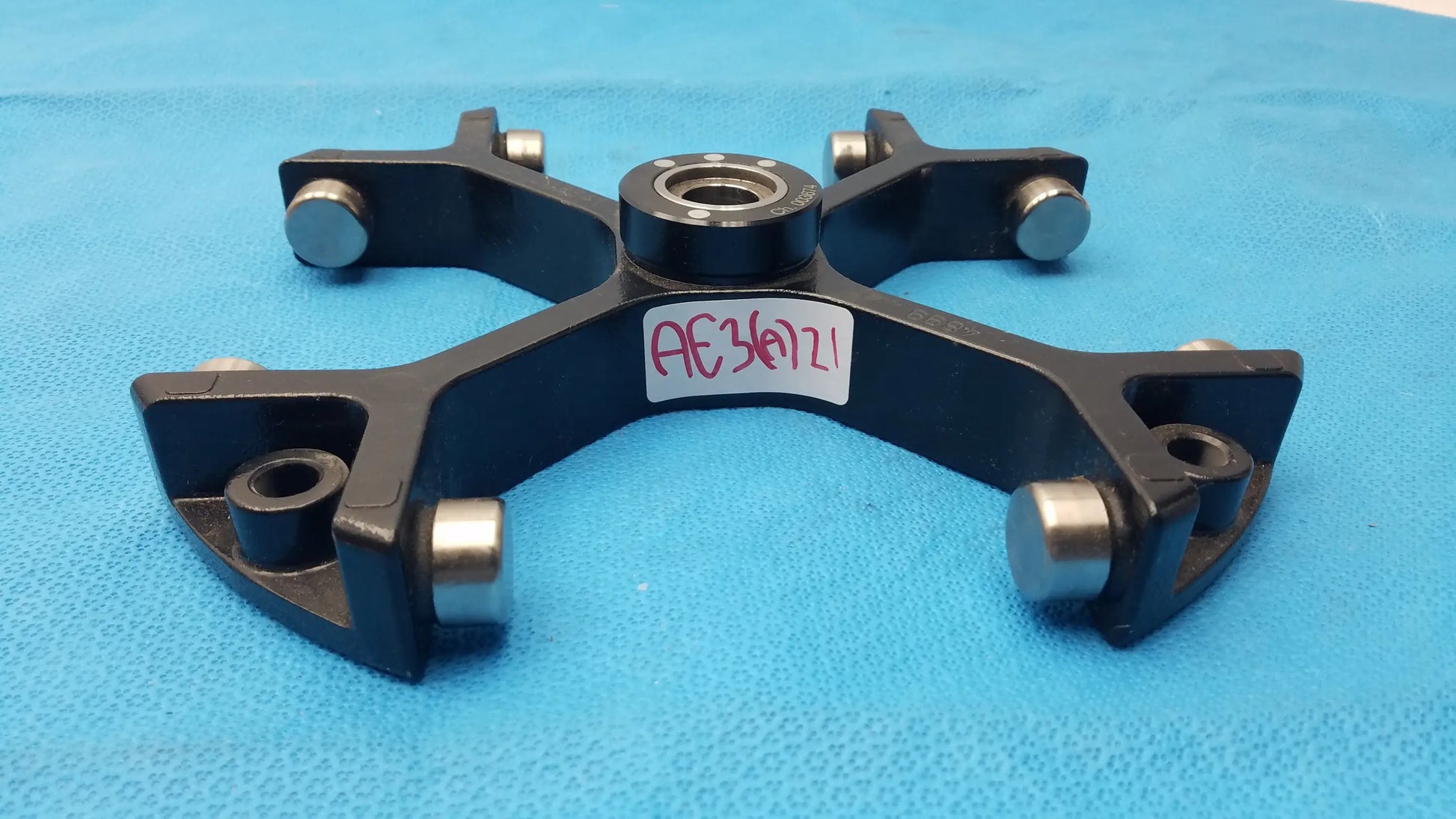 Black metal clamp with silver cylindrical knobs and central bearing marked ae340121 for reuse medical equipment