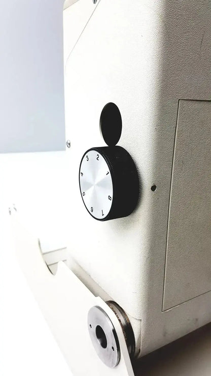 Black and silver dial with numbered markings on a white titmus optical ii vision tester industrial machine