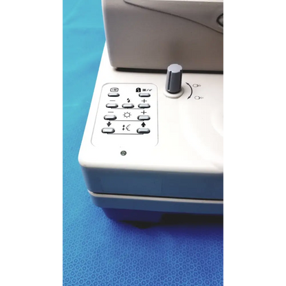 White electronic device with a control panel featuring buttons and a gray rotary dial.