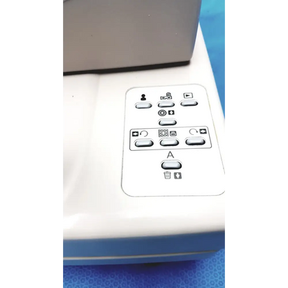 White plastic control panel with gray buttons and black icons, featuring a central ’a’ button surrounded by function symbols.