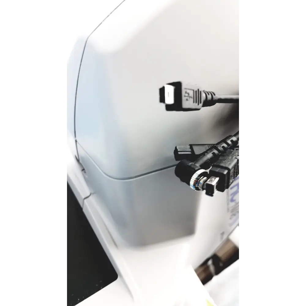 White plastic device with multiple black cables plugged into its side ports.