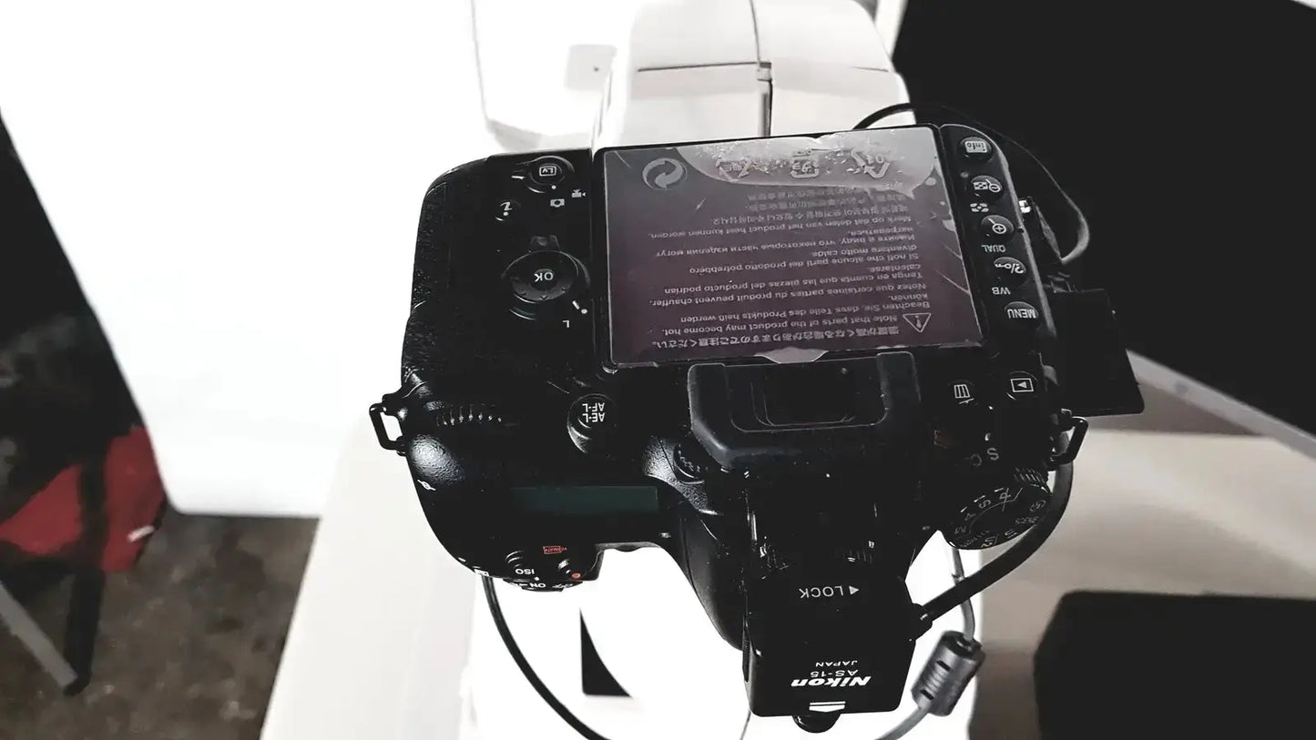 Black nikon dslr camera back with flip-out touchscreen displaying text and icons for topcon trc nw8 retinal use