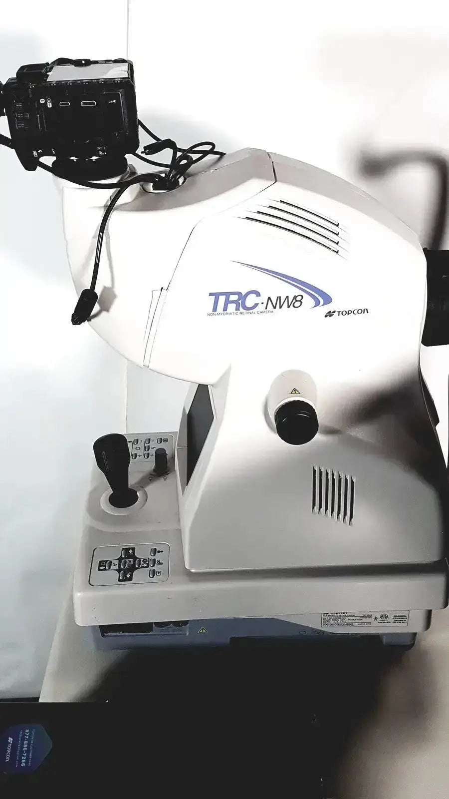 White Topcon TRC NW8 retinal camera with black control levers and mounted camera for automated refraction use