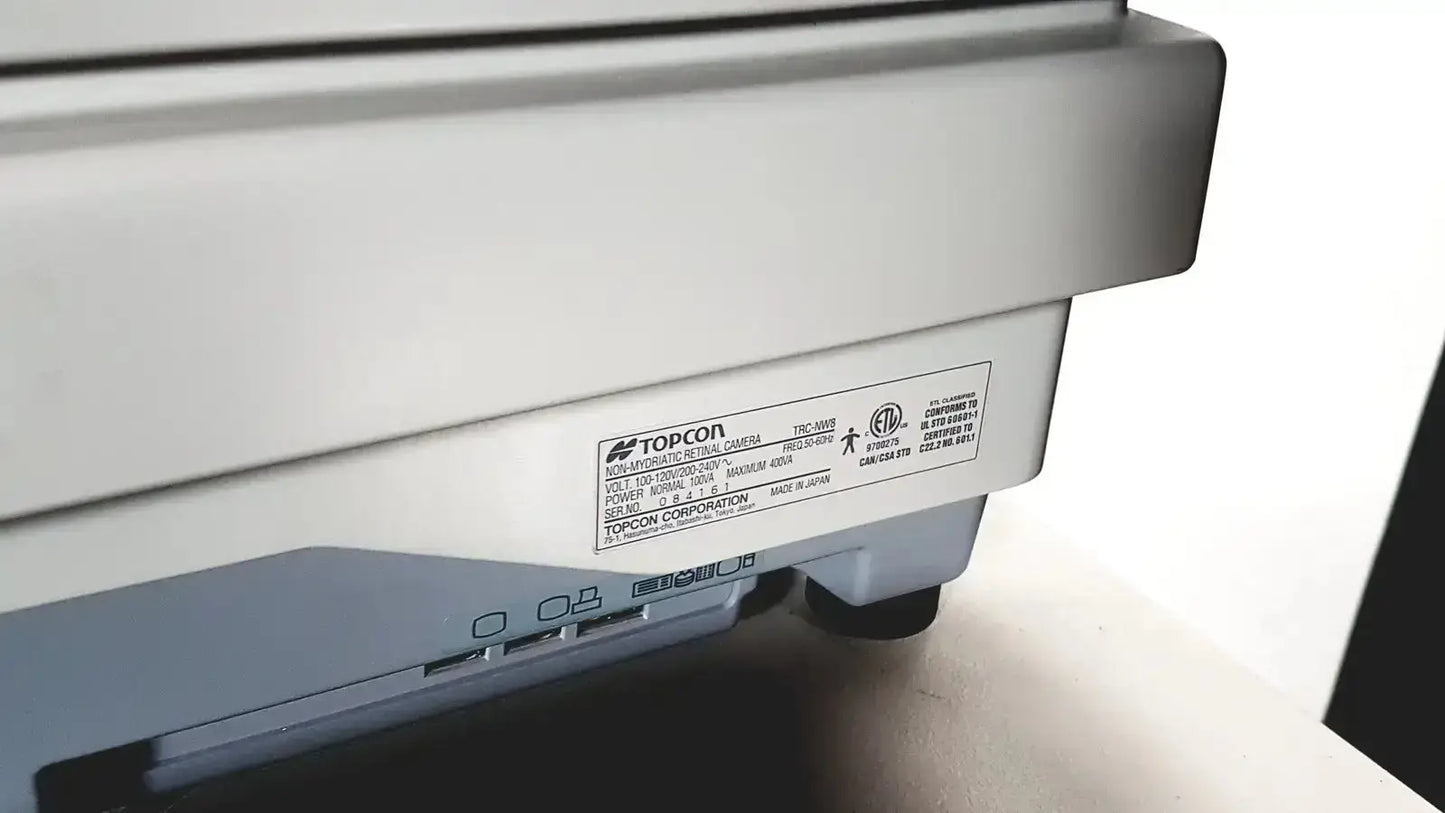 Gray plastic Topcon TSC-3085 multifunctional office printer with sleek design alongside Topcon TRC NW8 retinal camera system