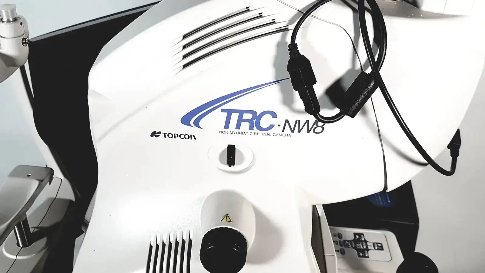 White Topcon TRC NW8 retinal camera with black cables and central control knob for precise retinal imaging use