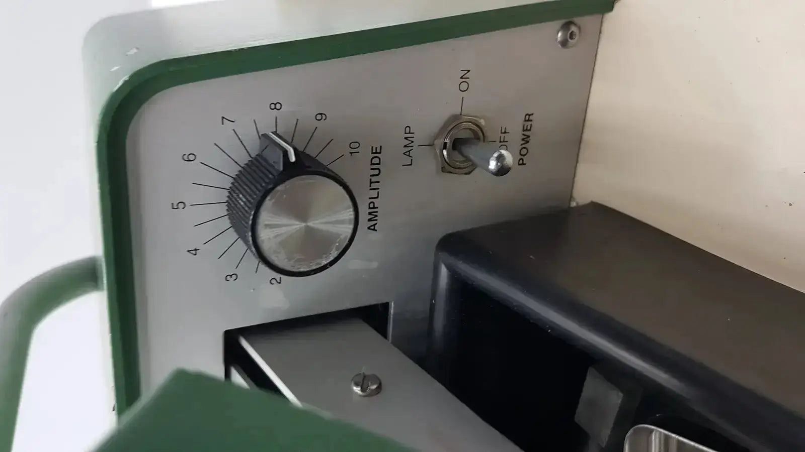 Green and silver vintage-style tpi vibratome series audio amplifier with rotary amplitude knob lamp switch and power toggle