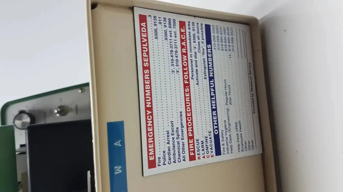 Beige metal emergency equipment box with emergency numbers label on tpi vibratome series 1000 sectioning system