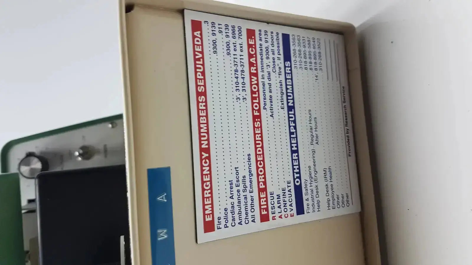 Beige metal emergency equipment box with emergency numbers label on tpi vibratome series 1000 sectioning system